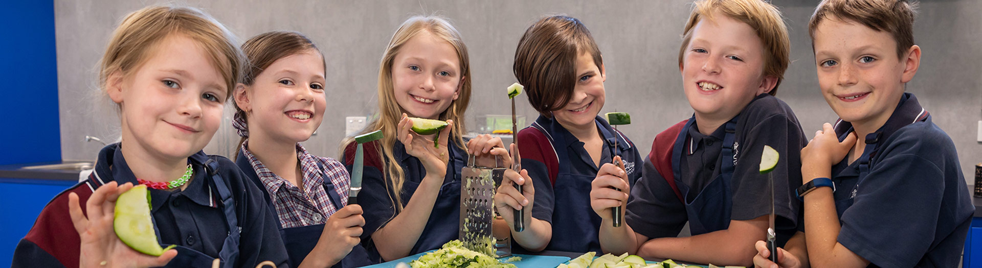smiling students grating zucchini in a school kitchen