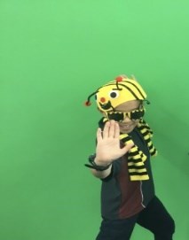 Kid dressed as a bee in front of a greenscreen